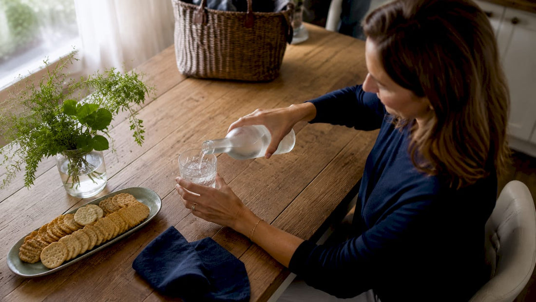 Woman pouring sparkling water at kitchen table